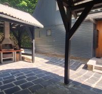 A cottage in Bukovec with a gazebo and an outdoor fireplace on a paved yard.