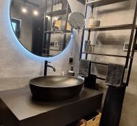 A bathroom in a cabin with a countertop sink, a round mirror, and storage baskets.