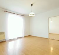 A bright room with a wood-decor floor in a 2-room apartment, curtain and light fixture.