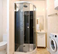A bathroom in a 2-room apartment with a washing machine, shower, and sink.