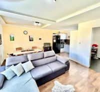 Living room in a family house with a sofa, dining table, and kitchen; floor with a wooden decor.