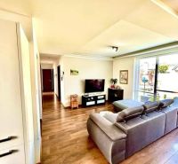 Living room in a family house with a wooden decor floor, a sofa, and a television.
