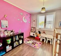 Children's room with a pink wall, toys, and a wooden decor floor in a family house.