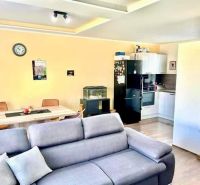 Living area of a family house with a kitchen, sofa, and floor with wooden decor.