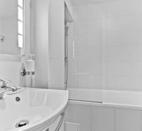 Bathroom in a 2-room apartment with a white sink and a bathtub on the left.
