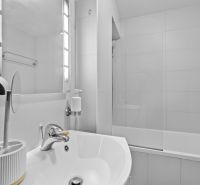 A bathroom in a 2-room apartment with a bathtub, mirror, and sink.