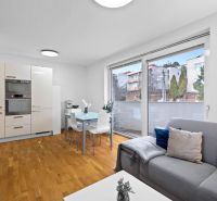 Living room with a kitchenette in a 2-room apartment with a wooden decor floor.