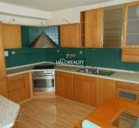 A kitchen in a 3-room apartment with a wooden decor floor and green tiles.