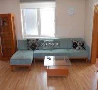 A living room with a blue sofa, a glass table, and a wooden decor floor in a three-room apartment.