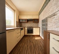 A kitchen in a 3-room apartment with a wooden decor floor and stylish surfaces.