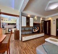 Living room and kitchen in a three-room apartment with a wooden decor floor.