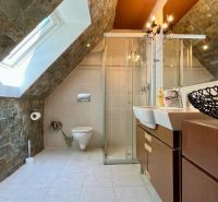 Attic bathroom with stone tiles and a shower in a family house.