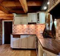 A kitchen in a family house with wooden beams, white cabinets, and tiles.