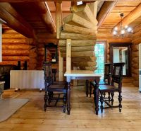 Interior of a family house with a wooden structure, fireplace, table, chairs, and a display cabinet.