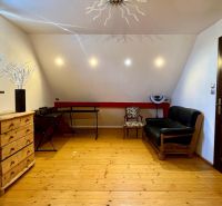 Attic room of a family house with wooden flooring, a sofa, and a brick wall.