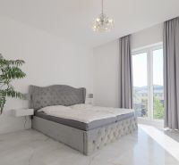 A bedroom in a family house with a gray bed, a houseplant, and ceramic flooring.