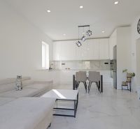 Interior of a family house with a white kitchen, sofa, and decorative elements on the walls.