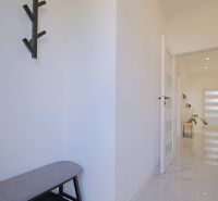 A hallway in a family house with a coat rack, a mirror, and a spacious passage.