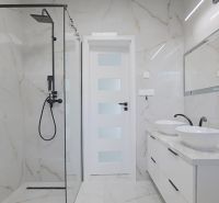 A bathroom with a walk-in shower and two sinks in a family house.