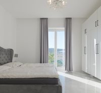 A bedroom with a large bed, white wardrobes, and curtains in a family house.