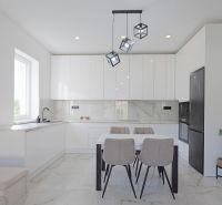 A kitchen in a family house with white cabinets, a dining table, and pendant lights.