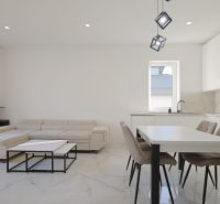 Living room with white walls, a kitchen unit, and a sofa in a family house.