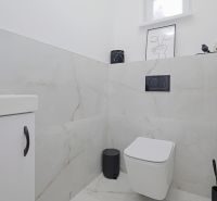A bathroom in a family house with light tiles and black fixtures.