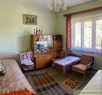 Living room in a family house with vintage furniture and a large window with lace curtains.