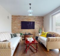 Living room in a family house with a brick wall, wooden decor, and a set of sofas.