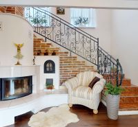 A fireplace with brick cladding next to the staircase in a family house, floor with wooden decor.
