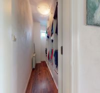A narrow hallway with cabinets and a wooden decor floor in a family house.