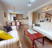 Living room in a family house with wood-patterned flooring, sofas, and a dining table.
