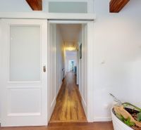 A hallway in a family house with a wooden decor floor and sliding doors.