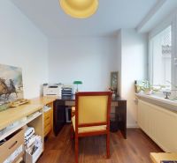 A study in a family house with a painting, a table, a chair, and a wooden-patterned floor.