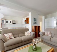 Living room of a 3-room apartment with comfortable sofas, decorations, and a wooden-patterned floor.