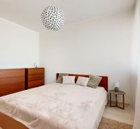 A bedroom in a 3-room apartment with a bed, a dresser, and a wooden decor floor.
