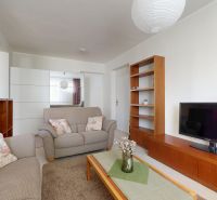 Living room in a 3-room apartment with comfortable sofas and wooden shelves.