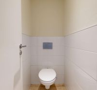 A toilet with white tiles in a 3-room apartment.