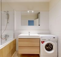 A bathroom in a 3-room apartment with a bathtub, sink, and washing machine.