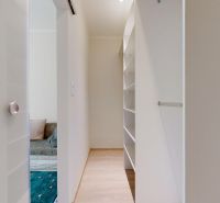 A narrow corridor with built-in shelves in a 3-room apartment leads to a relaxation nook.