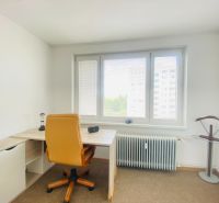 A study in a 3-room apartment with a window and a chair on a carpeted floor.