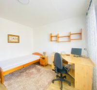 A room with a bed, carpet, table, and chair in a 3-room apartment.
