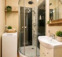 A bathroom with a corner shower, washing machine, and accessories in a 3-room apartment.