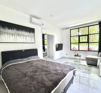 A bright bedroom with a large window, a comfortable sofa, and minimalist art on the wall.