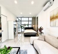 Bright living room with a bed in a villa, white walls, plants, mirror, and art.