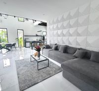 Interior of a villa with a comfortable gray sofa, geometric walls, and an open space.