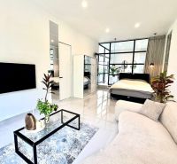 Living room of the villa with white furniture, plants, and a glass wall.