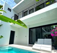 Bali villa with a pool and terrace, surrounded by greenery and flowers.