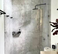 Bathroom in a villa with a plant, shower, and marble tiles.