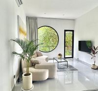A bright living room in a villa with a large round window and plants.